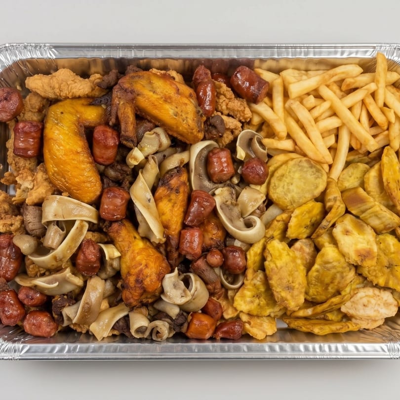 A large foil tray filled with fried chicken, sausages, fries, plantains, and mushrooms.