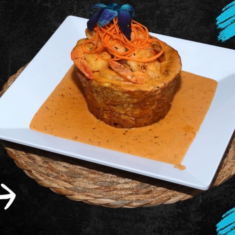 Shrimp dish in a crispy shell with orange sauce, garnished with carrot strips and blue flowers.
