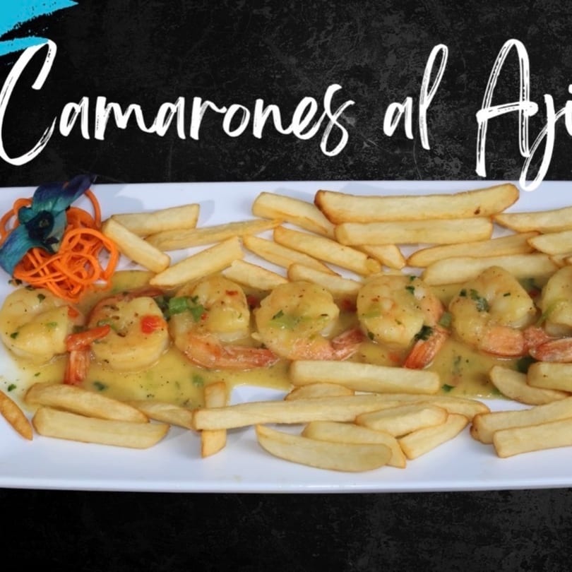 Camarones al Ajillo with french fries and a blue orchid garnish on a white plate.