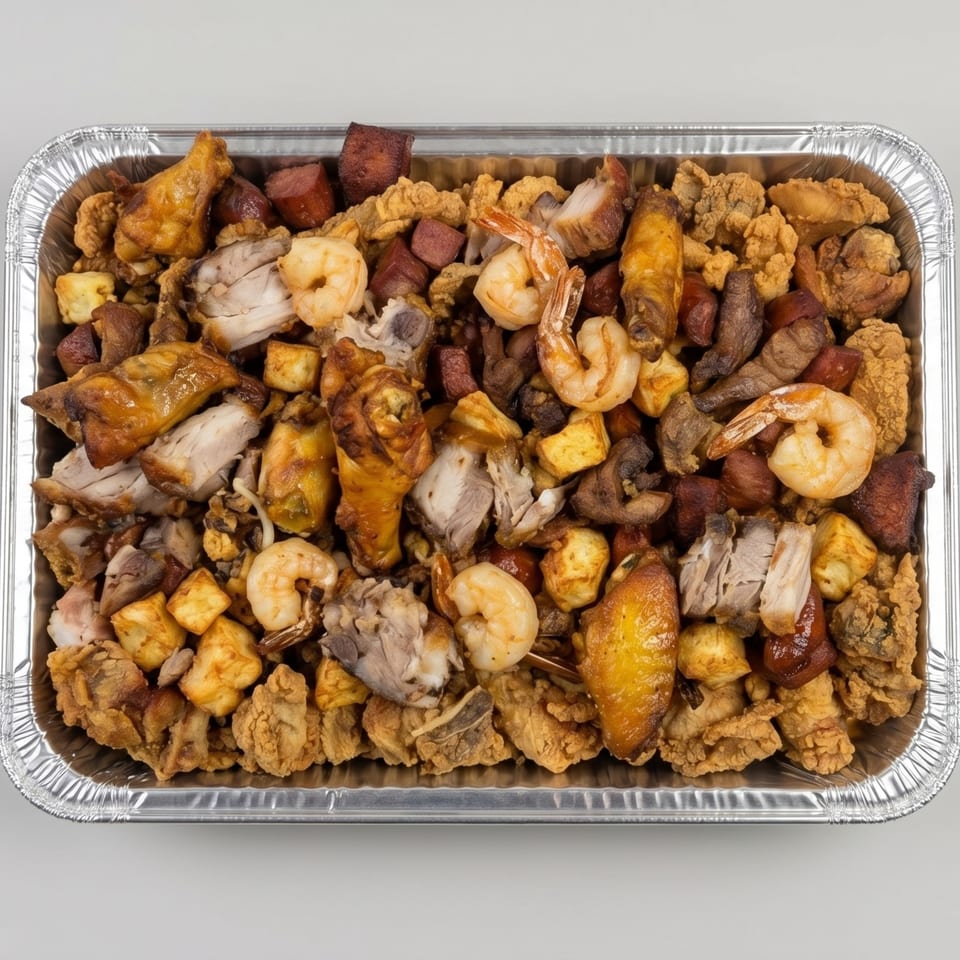A catering tray filled with fried chicken, shrimp, sausage, and other mixed meats.