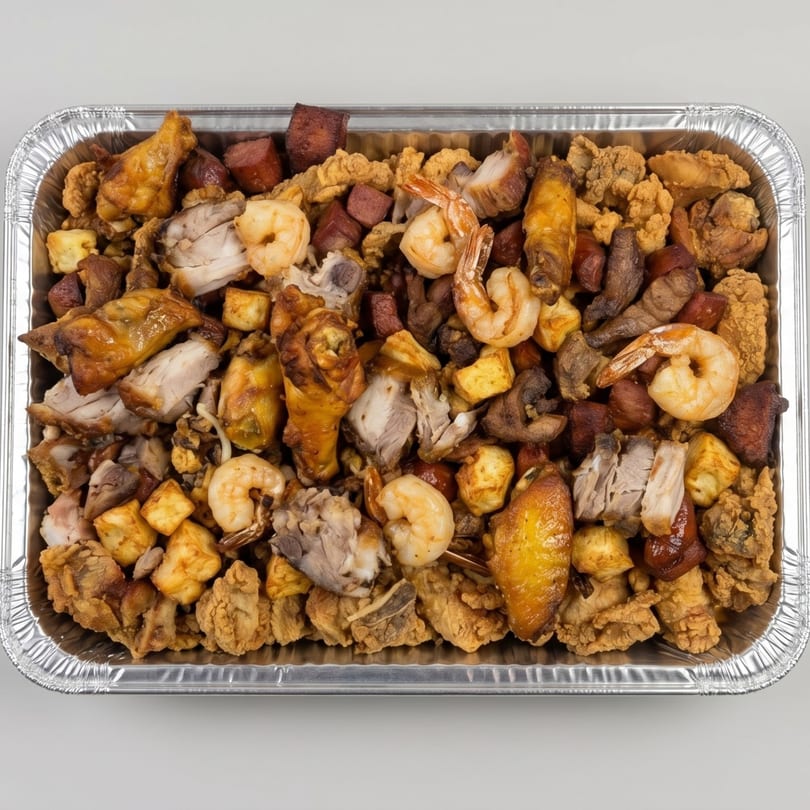 A catering tray filled with fried chicken, shrimp, sausage, and other mixed meats.